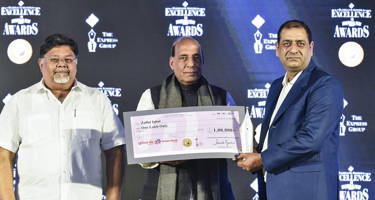 Home Minister Rajnath Singh presents a cheque to TV journalist Sheikh Zafar Iqbal as Indian Express Group MD Viveck Goenka looks on during the 13th edition of Ramnath Goenka Excellence in Journalism Awards, in New Delhi. PTI photo