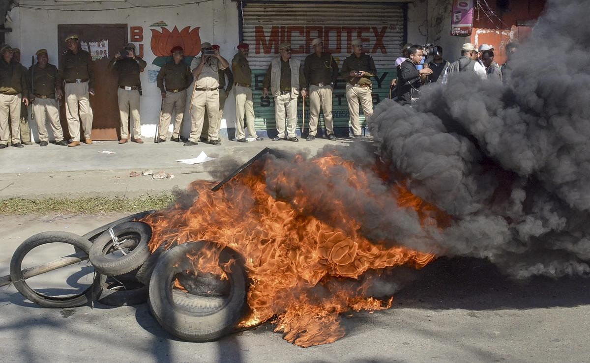 Police personnel look on as tyres are seen ablaze during a strike called by All Assam Students’ Union (AASU) and the North East Students’ Organisation (NESO) in protest against Citizenship (Amendment) Bill, in Dibrugarh. PTI Photo 