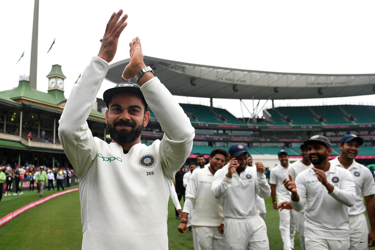 Virat Kohli gestures to supporters as his teammates celebrate a 2-1 series victory over Australia following play being abandoned on day five in the fourth test match between Australia and India at the SCG in Sydney. AAP/REUTERS