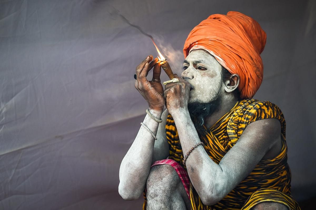 A sadhu smokes as he sits inside his tent among the Juna Akhara (a sadhu order) community at the Kumbh Mela festival. (AFP Photo)