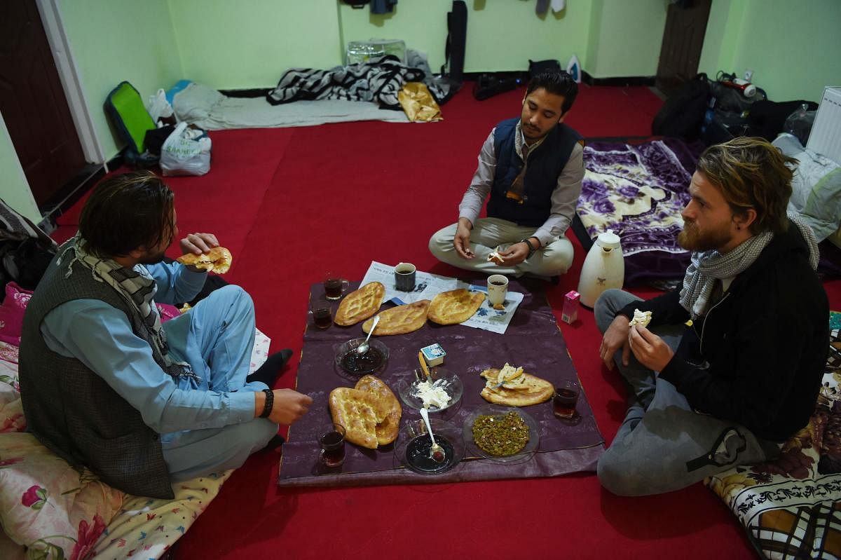 In this photo taken on November 11, 2018, Afghan Couchsurfing host Naser Majidi (C), 27, eats brekfast with his guests Norwegian tourist Jorn Bjorn Augestad (R), 29, and Dutch tourist Ciaran Barr, 24, at a house in Kabul. (AFP Photo)
