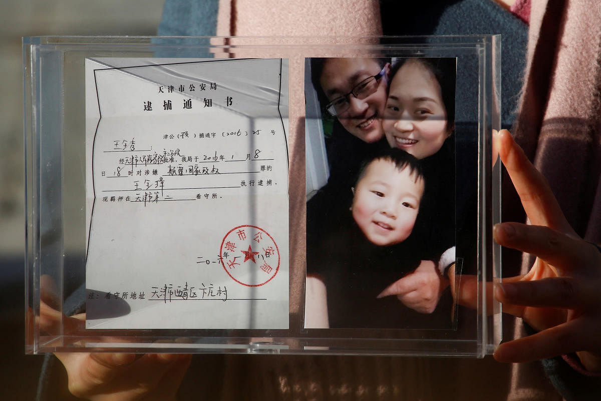 Li Wenzu, the wife of prominent Chinese rights lawyer Wang Quanzhang, holds a box with a family picture and the detention notice for her husband before shaving her head in protest in Beijing. Reuters.