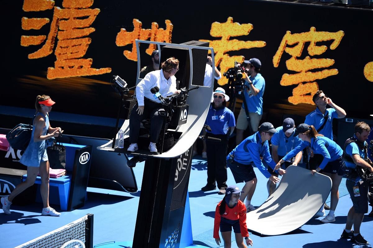Officials remove part of the umpire's canopy shade which was broken down by the spider-cam. AFP