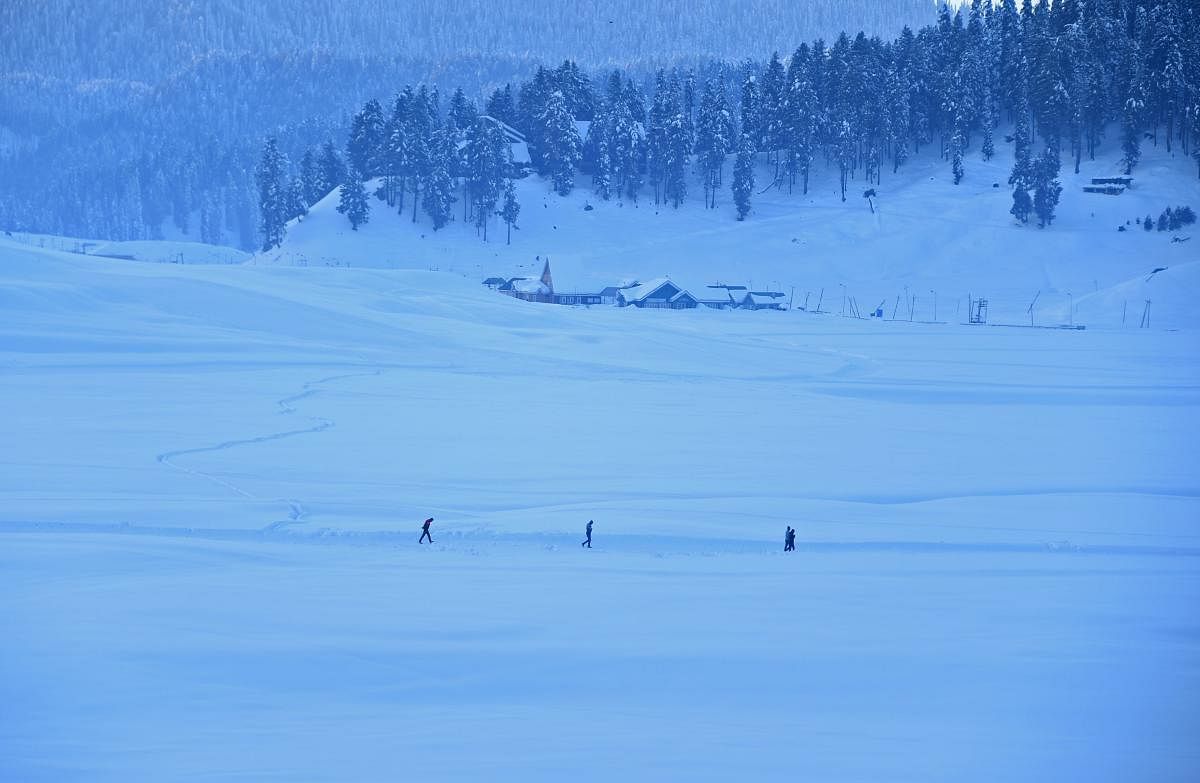 Tourists walk through a snow-covered area in Gulmarg, some 55 km north of Srinagar. AFP file photo.