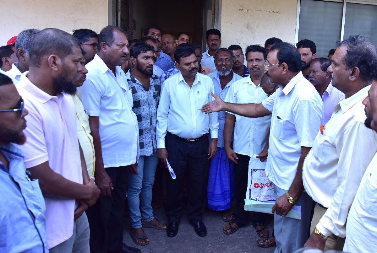 Fishermen interact with Fisheries Department Deputy Director Chikkaveera Nayak during a protest in Mangaluru on Tuesday.