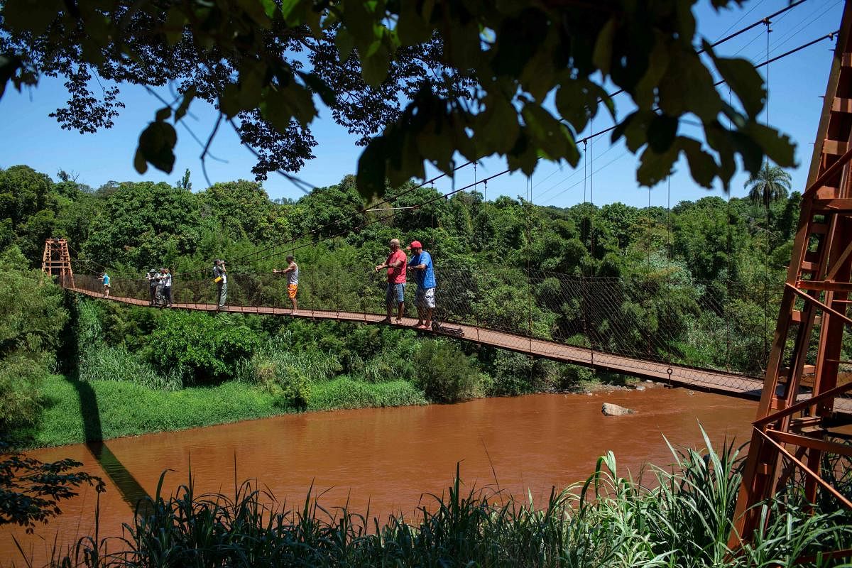 People stand on a bridge over the Paraopeba river, which was affected by mud, after the collapse of a dam at an iron-ore mine belonging to Brazil's giant mining company Vale near the town of Brumadinho, state of Minas Gerais, southeastern Brazil, on Janua