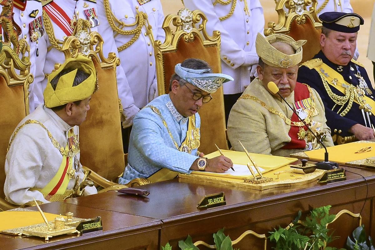 Sultan Abdullah Sultan Ahmad Shah, (2nd-L) signs a document after taking the oath at the National Palace in Kuala Lumpur. AFP