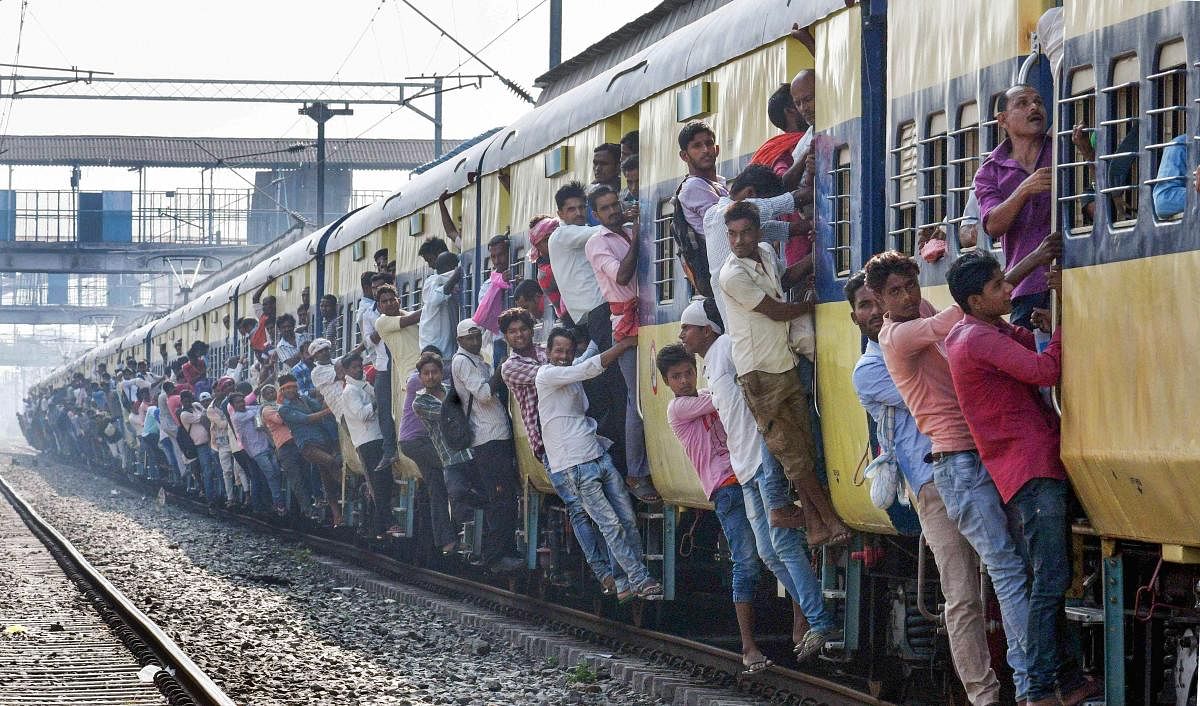 Commuters lean out of an overcrowded local train on the day of Railway Recruitment Board Examination (RRB), in Patna, in 2018. PTI