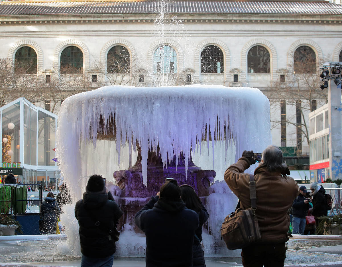 People photograph a mostly frozen Bryant Park fountain, as record low temperatures spread across the Midwest and Eastern states, in New York City (REUTERS)
