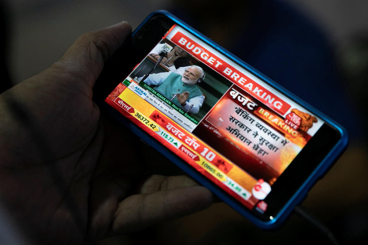 India's Prime Minister Narendra Modi is seen as a commuter watches telecast of the interim budget speech on his mobile phone at a railway station in Mumbai. (REUTERS)