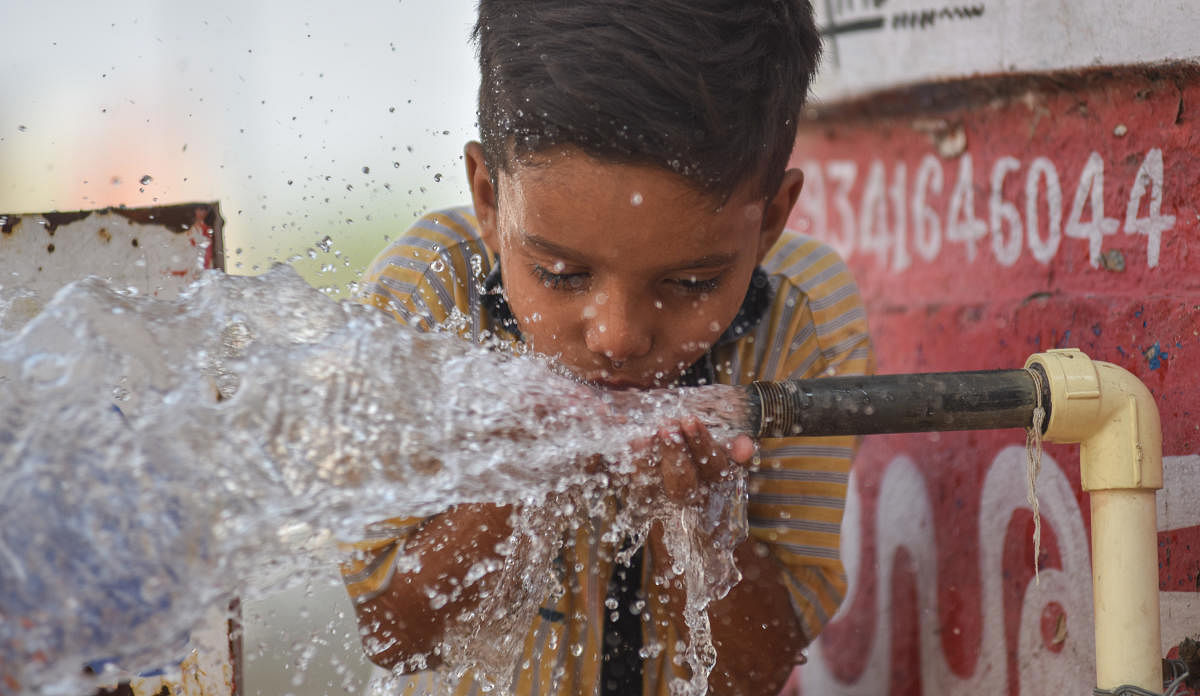 A boy drinks water from a bowerwell near SPV Circle in Kalaburagi. DH Photo/Prashanth HG