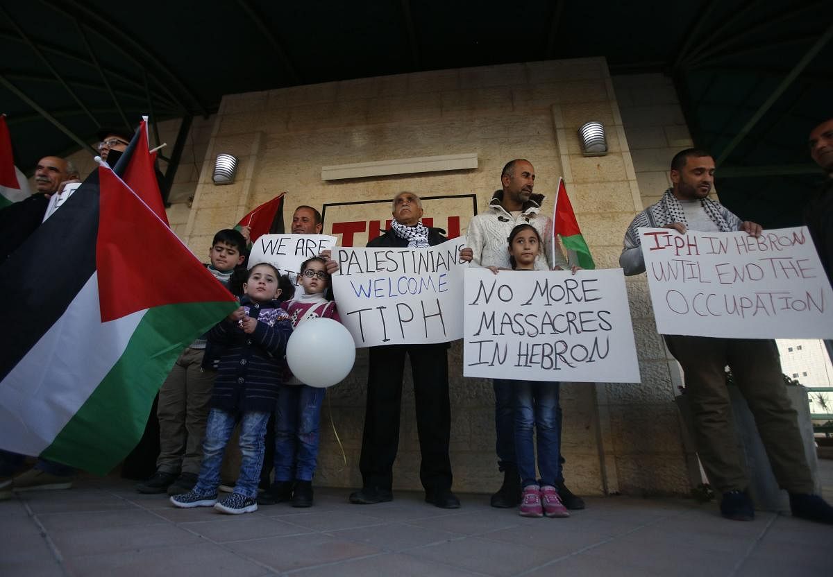 Palestinians carry national flags as well as placards denouncing the Israeli prime minister's recent decision not to renew the mendate of The Temporary International Presence in Hebron (TIPH), in the occupied West Bank city on January 30, 2019. (AFP)