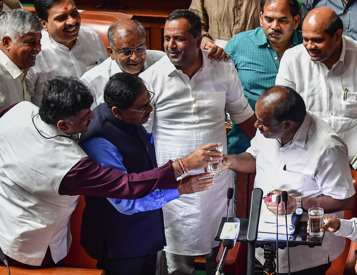 Minister D K Shivakumar and Deputy Chief Minister G Parameshwara offer a glass of water to Chief Minister H D Kumaraswamy after he completed his three-and-a-half-hour Budget speech in Bengaluru on Friday. DH Photo/Anand Bakshi