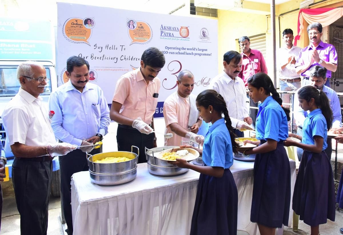 Deputy Commissioner Abhiram G Sankar serves hot food to students, during a programme, in Mysuru on Monday.