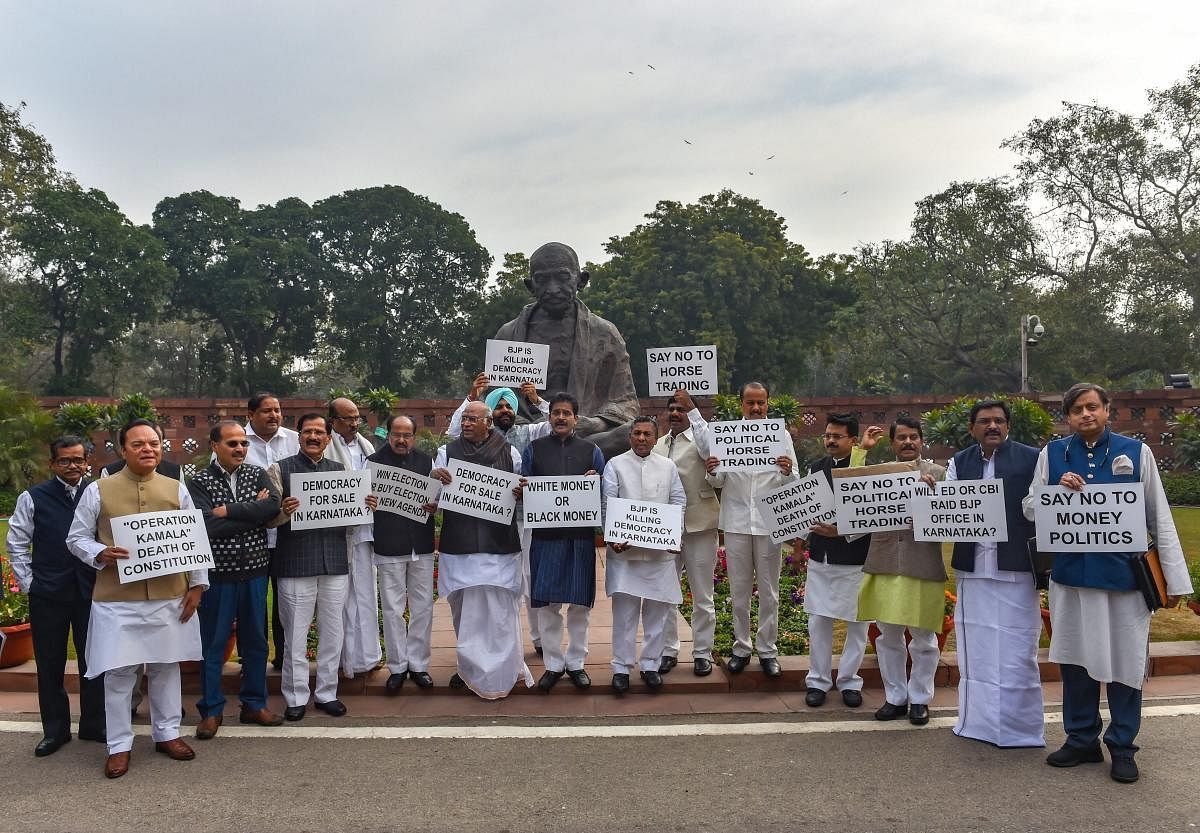 Congress MPs stage a protest against 'Operation Kamala' in Karnataka, in front of Mahatma Gandhi's statue in Parliament complex, New Delhi on Monday. PTI