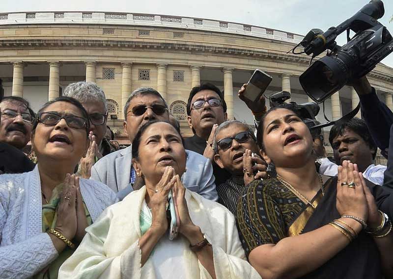 West Bengal Chief Minister and TMC supremo Mamata Banerjee with party MPs prays in front of the Mahatma Gandhi's statue inside Parliament complex in New Delhi on Wednesday. (PTI Photo)