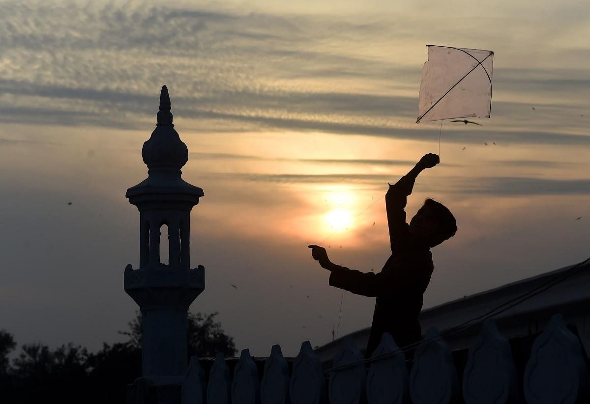 A Pakistani boy flies a kite on the roof of a mosque during sunset in Lahore on February 11, 2019. (Photo by ARIF ALI / AFP)