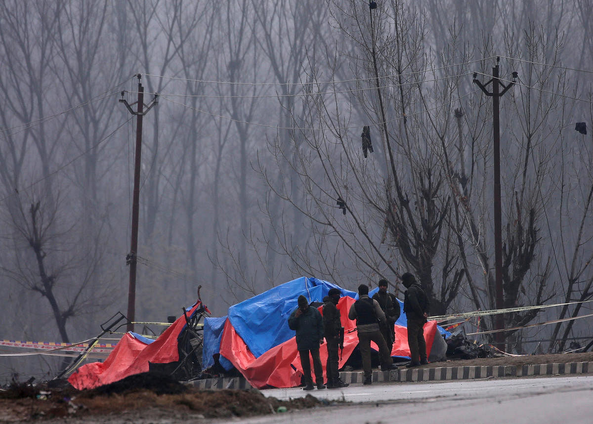 Forensic and security officials stand next to the wreckage of a bus after a suicide bomber rammed a car into the bus carrying Central Reserve Police Force (CRPF) personnel on Thursday, in Lethpora in south Kashmir's Pulwama district on Friday. (REUTERS)