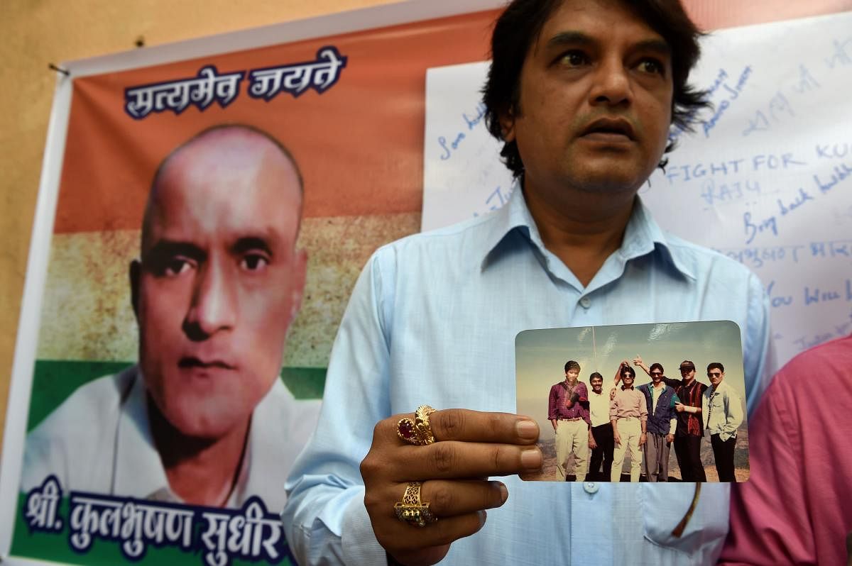 In this file photo taken on May 18, 2017 Indian friends of Kulbhushan Jadhav hold a photograph of them with Jadhav in the neighborhood where he grew up in Mumbai on May 18, 2017. - India will ask the UN's top court on February 18, 2019, to order Pakistan