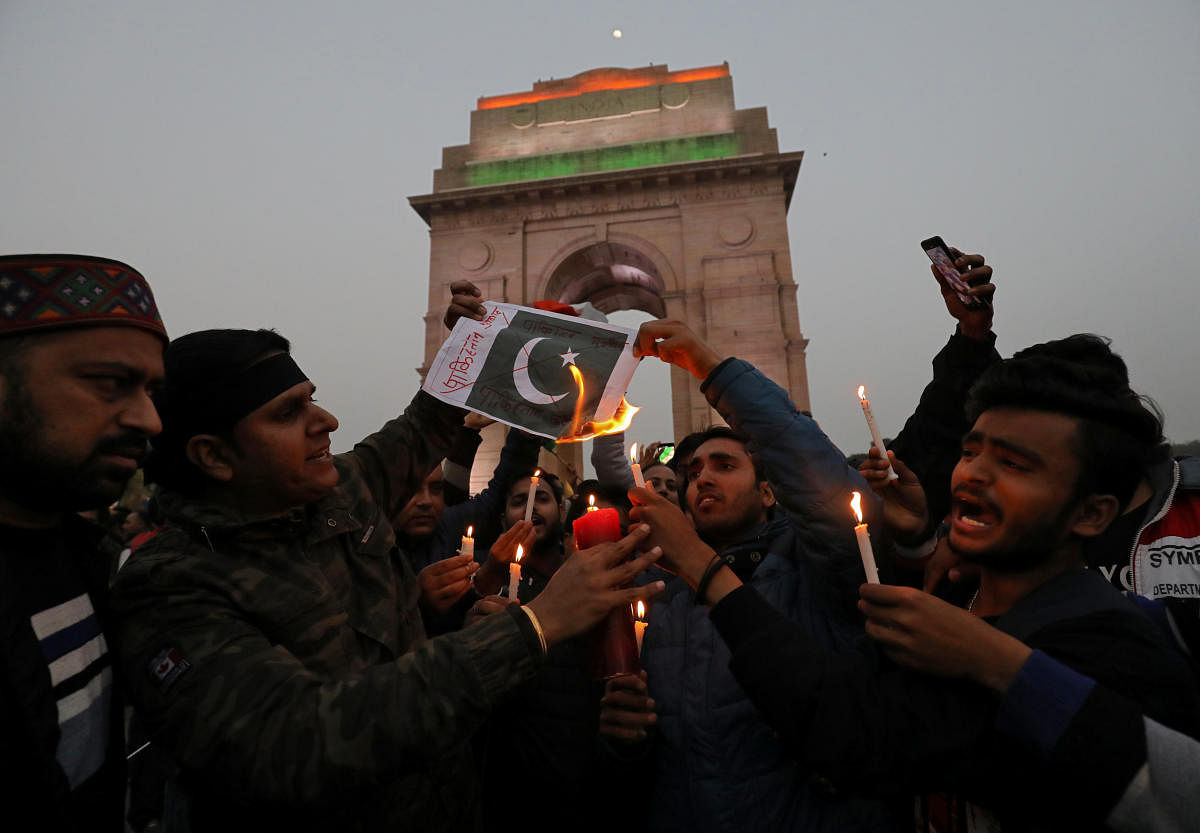 People burn a poster depicting a Pakistani flag during a candle light vigil to pay tribute to Central Reserve Police Force (CRPF) personnel who were killed after a suicide bomber rammed a car into the bus carrying them in south Kashmir on Thursday, in fro