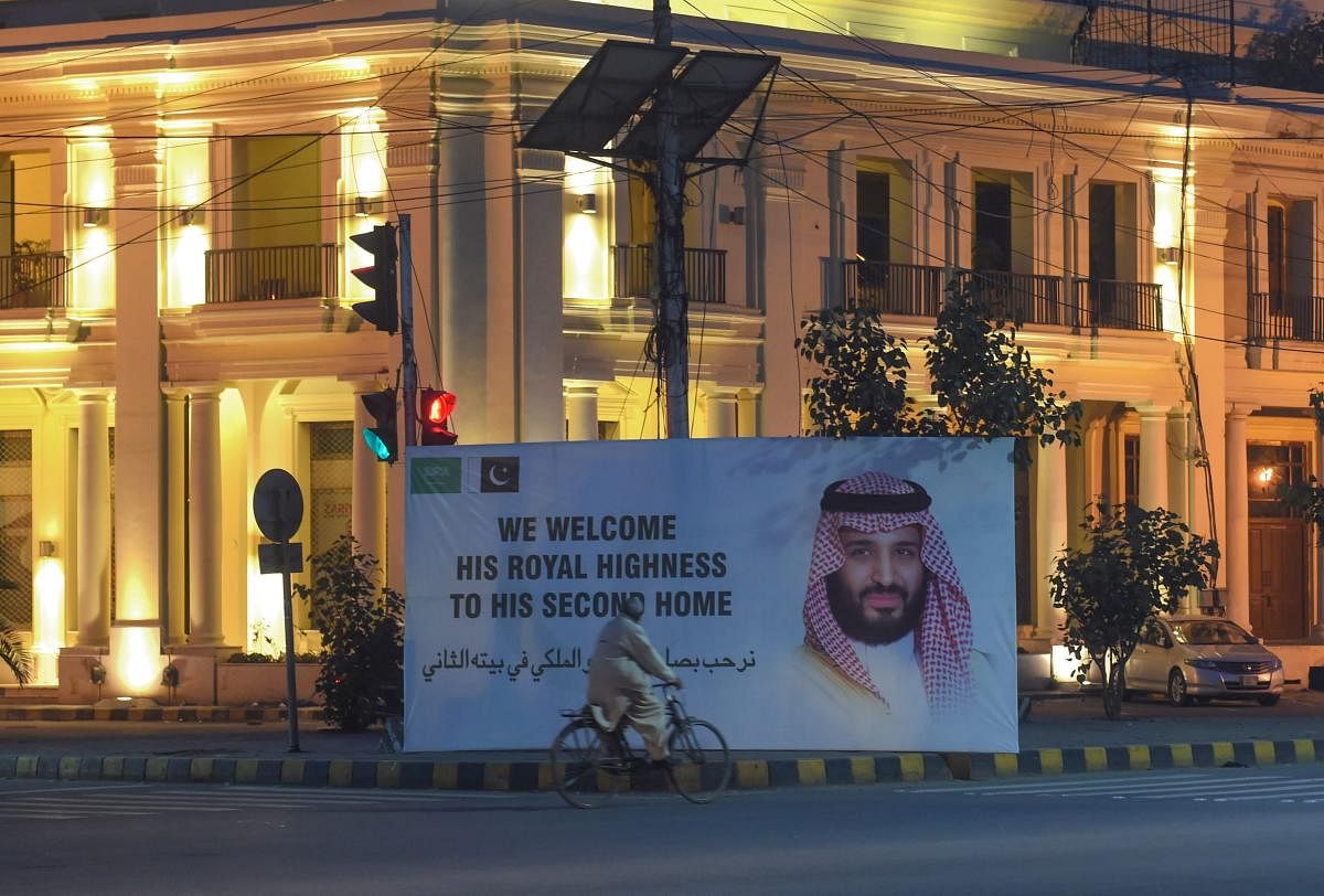 A Pakistani man rides past a billboard displaying a portrait of Saudi Arabian Crown Prince Mohammed bin Salman, ahead of the prince's arrival, in Lahore on February 16, 2019. - Saudi Arabian Crown Prince Mohammed bin Salman arrives in Pakistan on February