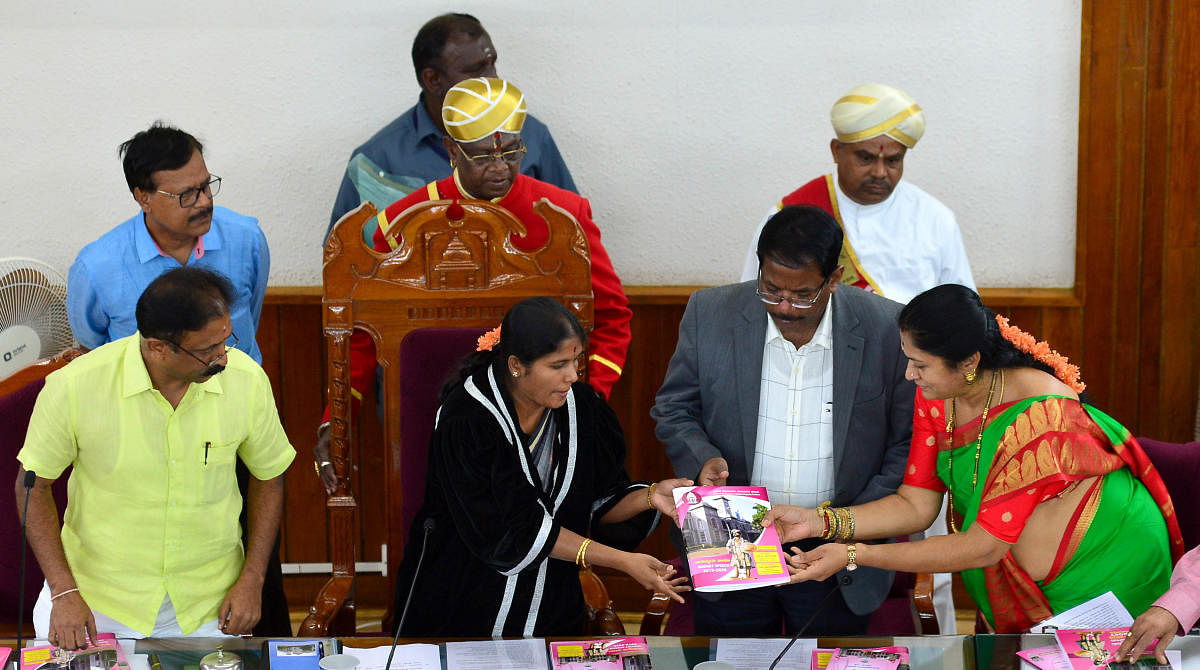 Councillor Hemalatha hands over the budget report to Mayor Gangambike Mallikarjun. (DH Photo)