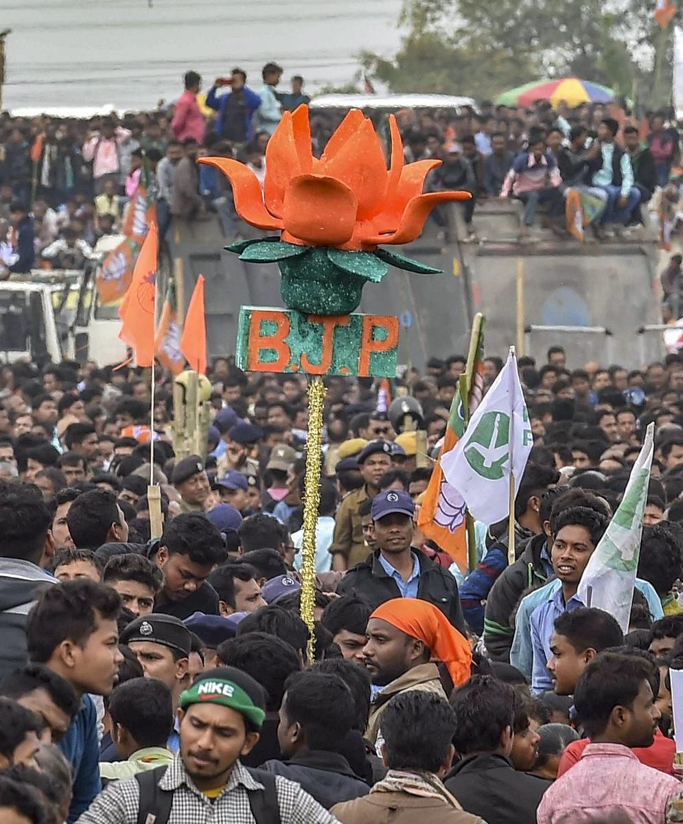 A BJP activist holds a model of party symbol 'lotus' as Prime Minister Narendra Modi addresses 'Save Democracy' rally at Churabhandar, Maynagiri in Jalpaiguri district of West Bengal, Friday, Feb 8, 2019.