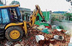 An earth mover deployed by the BBMP clears buildings that had come up illegally on Yelahanka lake bed, on Thursday.  DH Photo