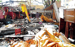 razed down: A fruit vendor picks up the remains of his shop which was demolished by the BBMP officials at the Malleswaram market on Saturday. DH Photo