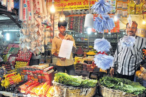bleak future: A Malleswaram market trader holds up the notice served on him by the BBMP to vacate the place, on Wednesday. DH photo