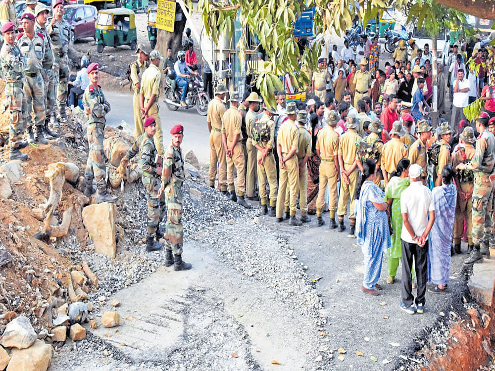 Residents and police in a discussion on the road that was razed by personnel of the Parachute Regiment Training Centre (PRTC) at Modi Garden near Kaval Byrasandra on Monday. DH PHOTO