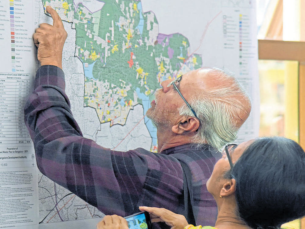 A senior citizen searches for the location of his property on the zone-wise map displayed by the BDA during the public consultation meeting on the draft Bengaluru Master Plan -2031 in Ramamurthy Nagar on Friday. DH&#8200;Photo