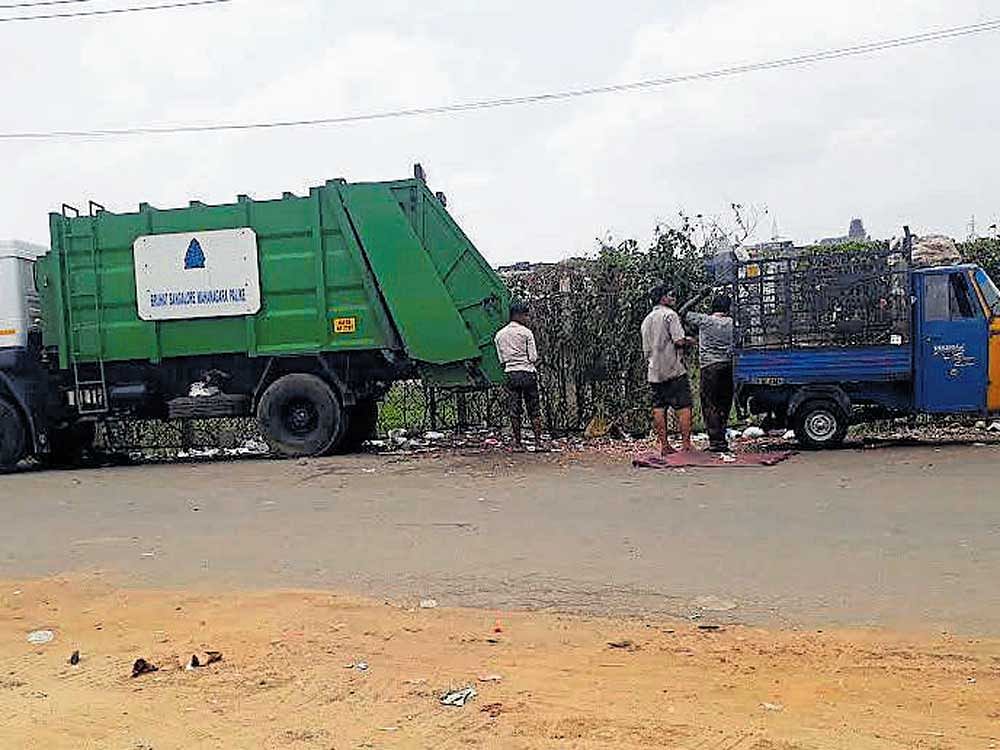 A BBMP garbage truck and a three-wheeler waste collector get ready to be unloaded on the Subramanyapura lakebed in the city.