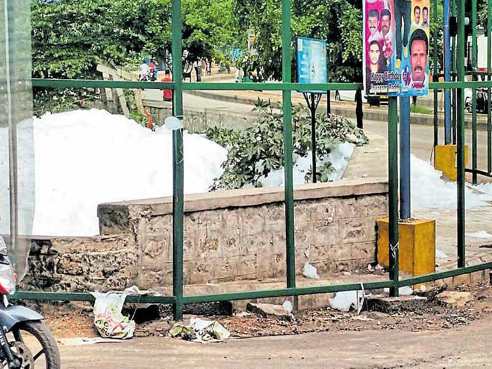 Froth flows out of Varthur lake on Sunday even as the mesh around its boundary has gone missing. DH photo