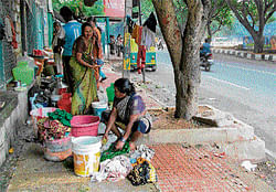 care of footpath: Dwellers of Ragigudda slum attend to their daily chores on the pavements. dh Photo