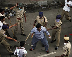 Indian policemen baton charge an activist, center, who allegedly pelted stones at them during a protest demanding the creation of a new state named 'Telangana' in Hyderabad, India, Sunday, Sept. 30, 2012. The protesters have been demanding that the new state be carved from the existing Andhra Pradesh state. (AP Photo