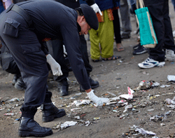 An Indian investigator looks for evidence in the debris at one of the two bomb blast sites in Hyderabad, India, Friday, Feb. 22, 2013. Indian police are investigating whether a shadowy Islamic militant group was responsible for a dual bomb attack that killed 16 people outside a movie theater and a bus station in the southern city of Hyderabad, a police official said Friday. AP Photo