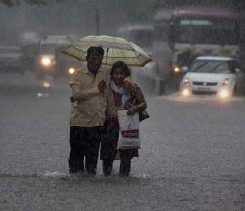 A couple walk in flooded water caused due to heavy rain in Thane on Sunday. PTI Photo