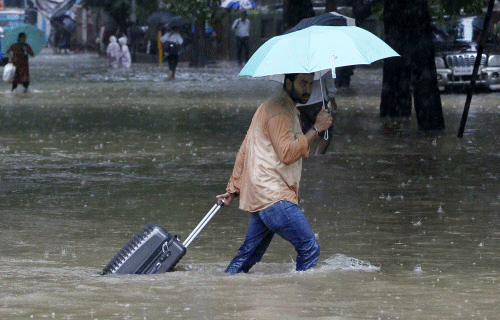 A man drags his suitcase through the street during heavy rain in Mumbai, Tuesday, July 23, 2013. (AP Photo