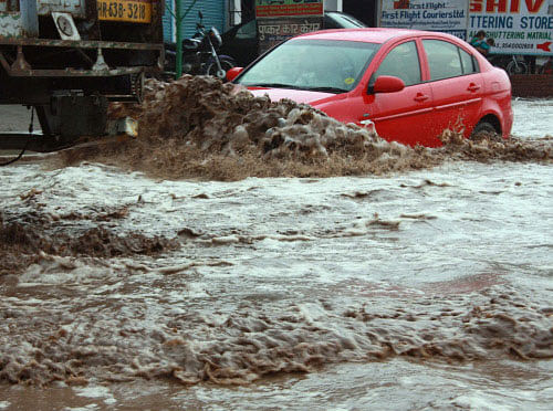 A car moves at a waterlogged road after heavy rains in Gurgaon on Thursday. PTI Photo