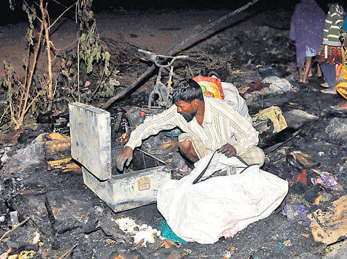 Slumdwellers search for their belongings after a fire broke out at Munenakolalu in the City on Tuesday.