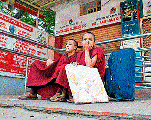 Two Buddhist monks are seen waiting near pre-paid auto counter at Sub-urban bus stand. DH Photo