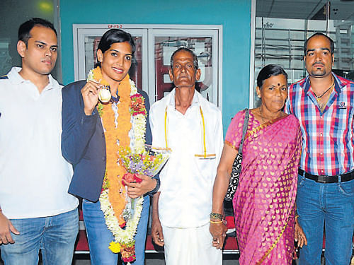 Indian women's Kabaddi team player Mamatha Poojary displaying her gold medal on her arrival at Mangalore International Airport on Friday. Husband Abhishek Kotian, father Boja Poojary, mother Kittu Poojarthi, brother Vishwanath among others look on. DH Photo