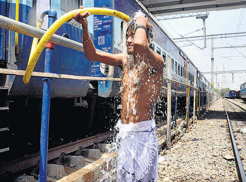 A man takes bath under a pipe supplying water to a train at a railway station in Allahabad on Saturday. PTI