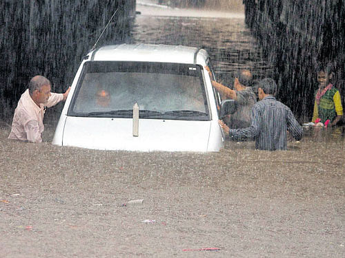People push a car on a waterlogged road in Faridabad on Monday. PTI
