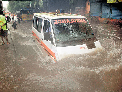 An ambulance moves along a waterlogged road near King's Circle area in central Mumbai on Friday. dh photo