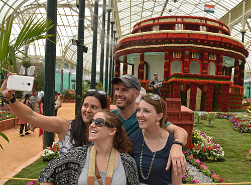 Visitors take a selfie in the backdrop of a replica of  Parliament House at Lalbagh on Saturday, as the  Independence Day flower show began. DH photo