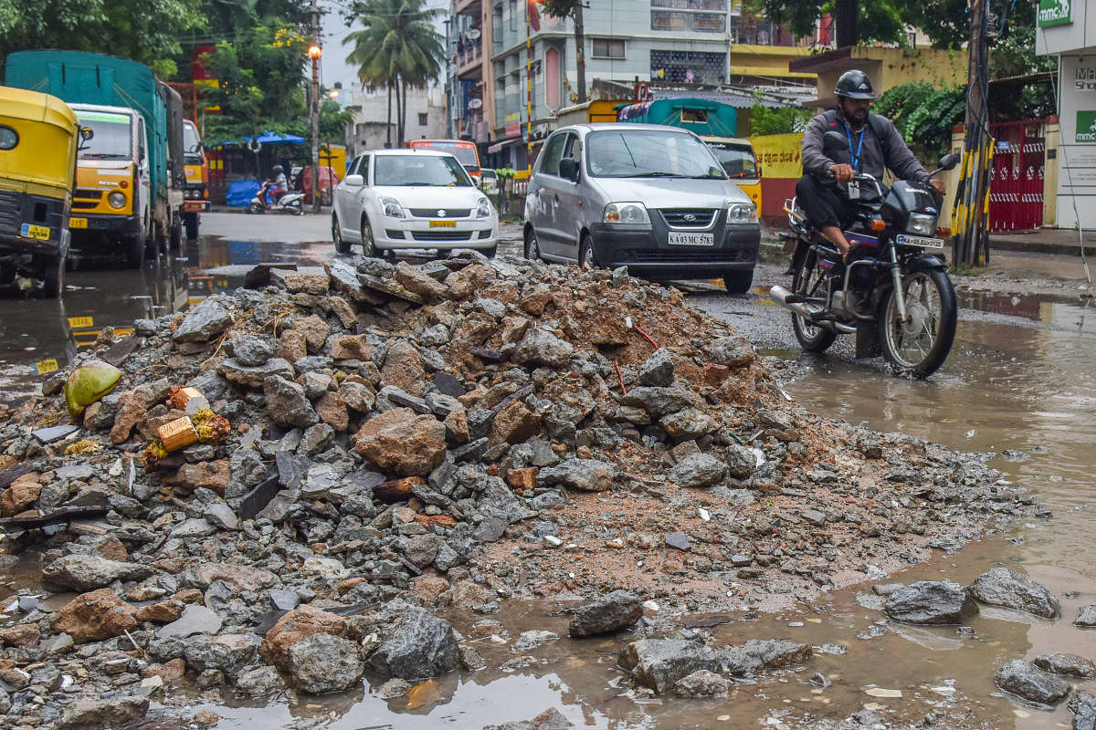 Building debris dropped on the road to fill potholes at Lakkasandra on Monday. DH Photo/S K Dinesh