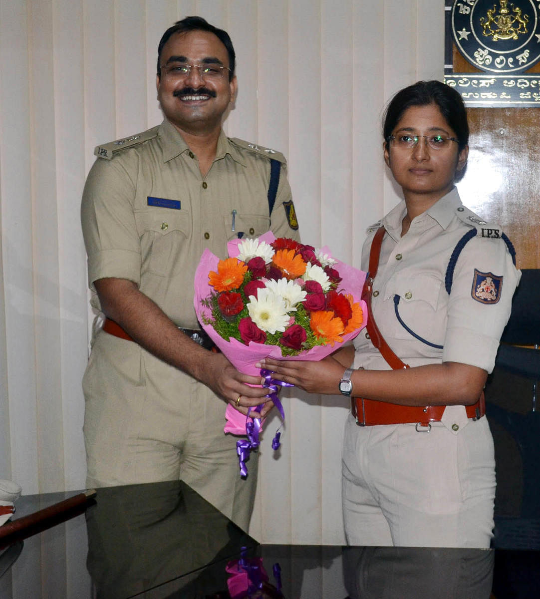 Outgoing Superintendent of Police Laxman Nimbargi greets newly appointed SP Nisha James in Udupi on Saturday. 