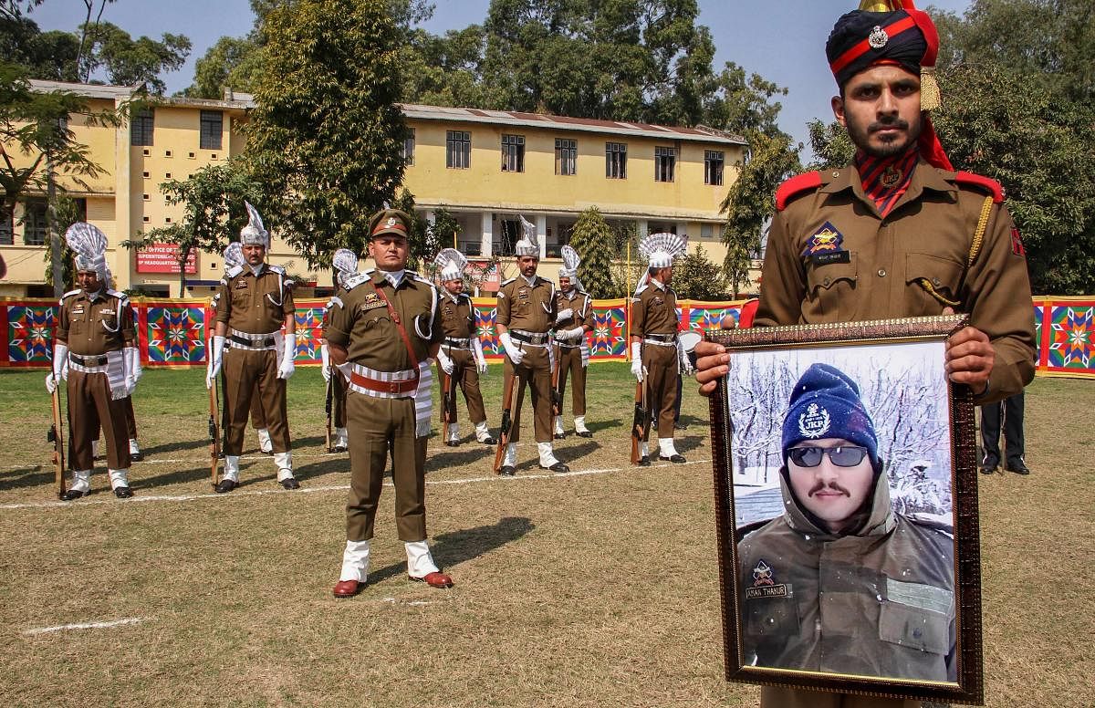 A police officer holds a portrait of Deputy Superintendent of Police Aman Kumar Thakur, who was killed in an encounter with militants in Kashmir's Kulgam district on Saturday, during a wreath laying ceremony in Jammu on Monday. PTI